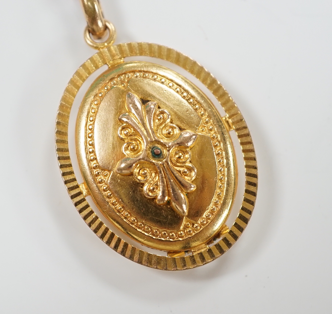 An embossed yellow metal oval pendant locket, 30mm, gross weight 9.6 grams.